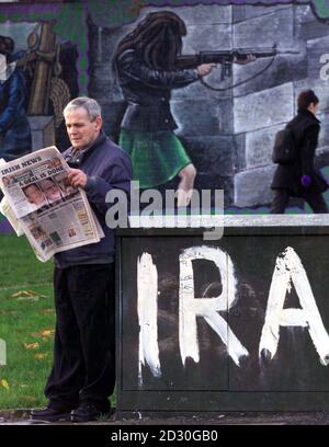 Un uomo a West Belfast legge il giornale locale di fronte a un murale IRA. Si ipotizza che l'IRA faccia una dichiarazione sulla sua posizione, in revisione dell'accordo di pace dell'Irlanda del Nord, dopo che Sinn Fein ha annunciato il suo sostegno. Foto Stock