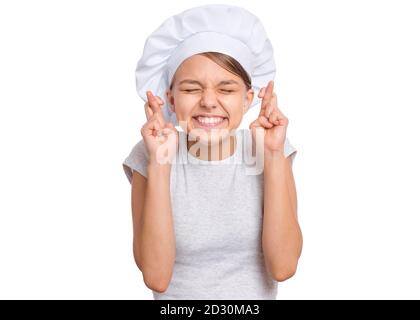 Teen girl in cappello chef, tenendo le dita incrociate e facendo desiderio, isolato su sfondo bianco. Foto Stock