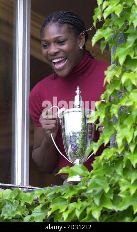 NESSUN USO COMMERCIALE : il tennista americano Serena Williams, che detiene il trofeo del vincitore, si pone da una finestra per i fotografi mentre celebra la vittoria della finale delle Ladies' Doubles con la sorella Venus, al Lawn Tennis Championships a Wimbledon. Foto Stock