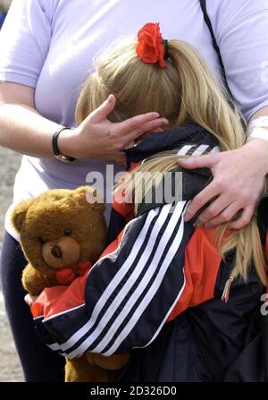 Momento di conforto per uno dei giovani della scuola primaria della Santa Croce Girl dopo essere stata scortata insieme ad altri allievi cattolici e genitori dalla scuola attraverso una tenuta protestante nella zona di Ardoyne a Belfast. Foto Stock