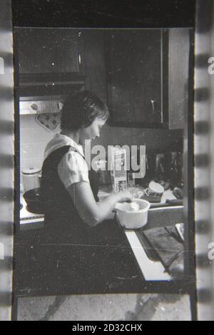 Fine 1970 vintage fotografia in bianco e nero di una donna che si cuoce in cucina. Foto Stock