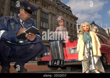 Un operaio del traffico prende un interesse in Lady Penelope e il suo maggiordomo Parker, da Thunderbirds, con la FAB 1 auto su Regent Street, 37 anni dopo che sono saliti nel loro roadster rosa. Gli articoli originali saranno venduti all'asta al Planet Hollywood, Londra. Foto Stock