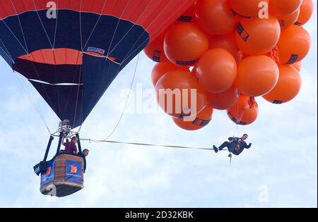 Mike Howard che penzolante sotto centinaia di palloncini pieni di elio alla Bristol Balloon Fiesta. Howard, vestito da suo eroe temerario in una giacca da cena, è salito a più di 7.000 piedi ma non è riuscito a salire abbastanza in alto per rompere il record mondiale di 11.000 piedi a causa della copertura pesante della nuvola. Foto Stock