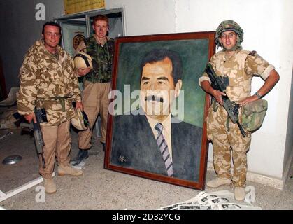 (L-R) Capt Joe Power, Maj Andrew Britton e Capt Simon Ridgway si trovano vicino alla foto di Saddam nel foyer presso il quartier generale della festa di Ba-ath a Basra, mentre lo squadrone di Cyclops del 2° Regiment reale dei carri armati prende la città nel sud dell'Iraq. Foto Stock