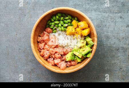 Colpo di testa di una gustosa ciotola di poke con salmone, riso, avocado, mango e fagioli di edamame. Tipico cibo Hawaiiano Foto Stock