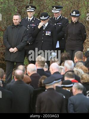 Altri offendenti della polizia, tra cui il capo della polizia scozzese Constable Sir Stephen House (secondo da sinistra), assistono al funerale del Constable di polizia Tony Collins, mentre la sua bara è portata per la sepoltura al cimitero di Lamlash sull'isola di Arran. Foto Stock