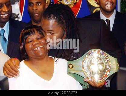 Il campione mondiale dei pesi massimi Lennox Lewis bacia sua madre Violet mentre tiene la sua cintura WBC durante una conferenza stampa alla Grosvenor House, Londra, dove ha annunciato il suo ritiro dalla boxe. Il 38-year-old è diventato soltanto il terzo detentore del titolo nella storia della divisione camminare via con la sua cintura intatta. Foto Stock