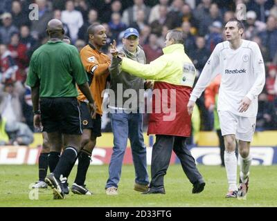 Un fan di Wolverhampton Wanderers (al centro) è tenuto lontano da Paul Ince (seconda a sinistra) e da un amministratore (seconda a destra) dell'arbitro Uriah Rennie (a sinistra) dopo che Bolton Wanderers ha segnato il gol vincente, durante la partita di Barclaycard Premiership a Molineux, Wolverhampton, lunedì 12 aprile 2004. Bolton Wanderers ha vinto 2-1. PA Foto: Nick Potts. Foto Stock