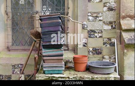 Vassoi da giardino fiorito setaccio e scopa proppato contro il muro della chiesa Foto Stock