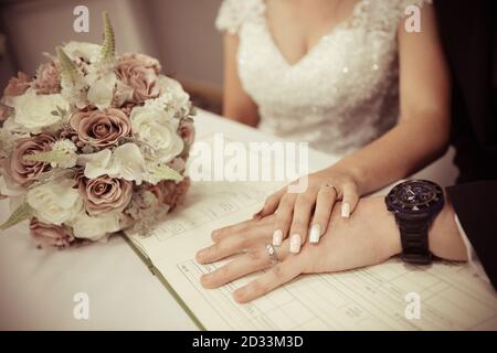 Coppia di nozze che mostra gli anelli di nozze sul registro di matrimonio di nozze Foto Stock