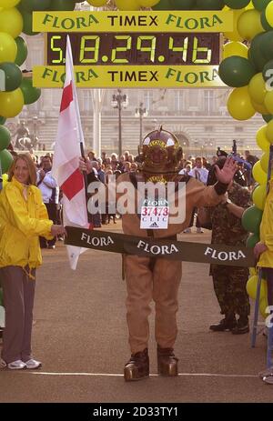 Lloyd Scott attraversa il traguardo della maratona di Londra, Lloyd è il corridore maratano più lento di sempre, 'corse' il corso indossando un'antica tuta subacquea in sei giorni. Lloyd spera di essere cresciuto nella regione del 100,000 a sostegno del cancro e della leucemia in Infanzia dai suoi sforzi. Foto Stock