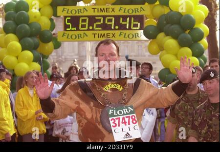 Lloyd Scott attraversa la linea di arrivo della maratona di Londra, Lloyd il corridore maratano più lento di sempre, 'corse' il corso indossando un'antica tuta subacquea in sei giorni. Lloyd spera di aver cresciuto nella regione del 100,000 in aiuto di cancro e leucemia in Infanzia dai suoi sforzi. Foto Stock