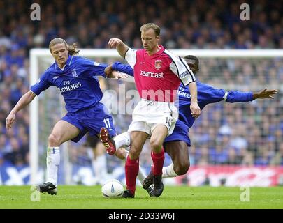 Dennis Bergkamp di Arsenal tiene fuori i tackles da Emmanuel Petit di Chelsea (a sinistra) & Marcel Desailly (a destra) durante la partita finale della fa Cup sponsorizzata da AXA tra Arsenal e Chelsea al Millennium Stadium. QUESTA IMMAGINE PUÒ ESSERE UTILIZZATA SOLO NEL CONTESTO DI UNA FUNZIONE EDITORIALE. NESSUN UTILIZZO DI SITI WEB/INTERNET A MENO CHE IL SITO NON SIA REGISTRATO PRESSO LA FOOTBALL ASSOCIATION PREMIER LEAGUE. Foto Stock