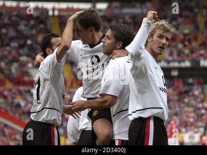 David Beckham (a destra) del Manchester United saluta i fan dei viaggi mentre i compagni di squadra Gary Neville e Ryan Giggs celebrano l'obiettivo di Ruud van Nistelrooy contro Charlton, durante la loro partita di premiership fa Barclaycard al Charlton's Valley Ground, Londra. QUESTA IMMAGINE PUÒ ESSERE UTILIZZATA SOLO NEL CONTESTO DI UNA FUNZIONE EDITORIALE. NESSUN UTILIZZO DI SITI WEB/INTERNET A MENO CHE IL SITO NON SIA REGISTRATO PRESSO LA FOOTBALL ASSOCIATION PREMIER LEAGUE. Foto Stock