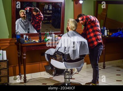 il suo stile perfetto. l'uomo vuole una nuova acconciatura. bellezza e moda maschile. uomo maturo al barbiere. uomo brutale al parrucchiere. barbiere con cliente maschile. hipster con barba tinta e baffi. Foto Stock