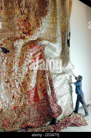 Un tecnico effettua alcune regolazioni finali al 'panno d'oro' di El Anatsui di 6m x 8m. Foto Stock