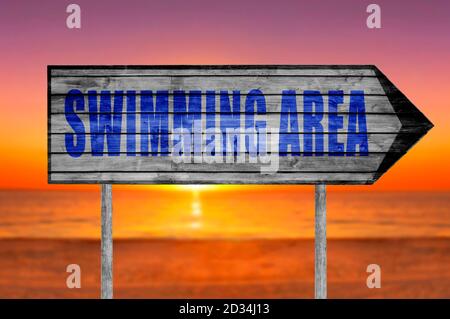 Spiaggia zona di nuoto segno di legno con una spiaggia sullo sfondo Foto Stock