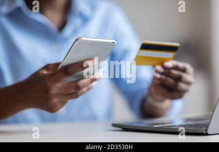 Trasferimenti di denaro. Inriconoscibile Businesswoman nero utilizzando smartphone e carta di credito per i pagamenti Foto Stock