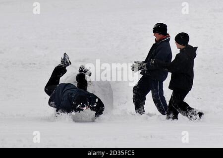 Un ragazzo cade su una grande palla di neve in Harrow-on-the-Hill, Middlesex dopo una pesante nevicata nel Regno Unito. Foto Stock