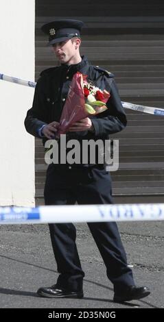 Un Garda con fiori fuori dal pub Faussagh House a nord di Dublino dove Eamon Dunne, 32, da Dunsoghly Drive a Finglas, è stato ucciso. Foto Stock