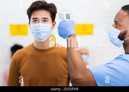 Infermiera che fa lo screening della temperatura per l'uomo asiatico in ospedale Foto Stock