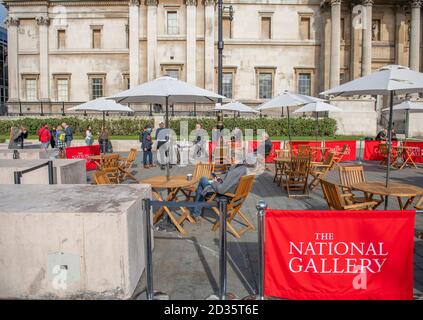 Westminster, Londra, Regno Unito. 7 ottobre 2020. Alcuni visitatori socialmente distanziati dell'improvvisato caffè all'aperto della National Gallery di Trafalgar Square godono del sole d'autunno. Credit: Malcolm Park/Alamy Live News. Foto Stock