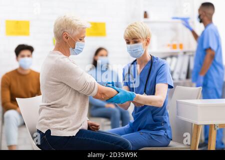 Donna anziana del paziente che ottiene vaccinata contro Coronavirus seduto in ospedale Foto Stock