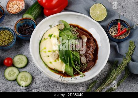 Guance di vitello in salsa con patate e cavolo, decorate con erbe Foto Stock