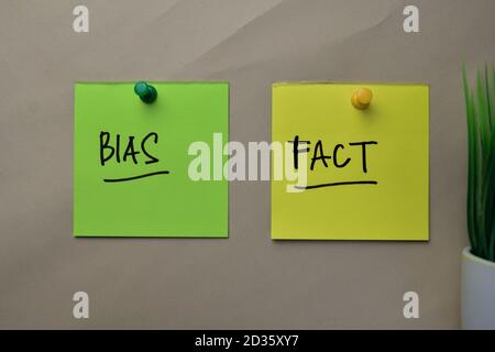 Bias e scrittura di fatti su note appiccicose isolate sulla scrivania dell'ufficio. Foto Stock