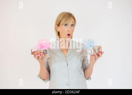 Donna bionda matura che guarda la macchina fotografica che tiene i regali sul bianco sfondo Foto Stock