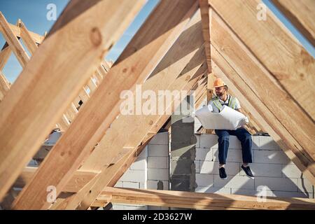 Gioioso uomo che indossa un hardhat e che tiene un modello Foto Stock