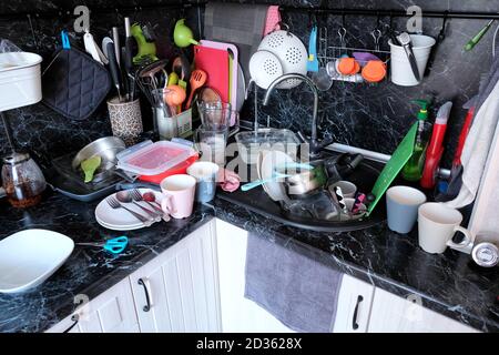 Piatti sporchi nel lavandino della cucina e sul piano di lavoro. Non ha fatto le faccende domestiche in cucina. Molti piatti sporchi dopo la cottura. Foto Stock