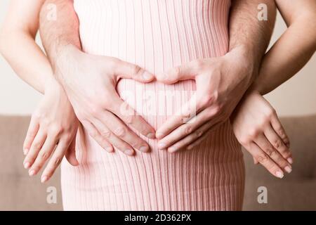 Gravidanza, attesa di un paio di bambini. Futuri genitori con mani in forma di cuore. L'uomo mise la mano sulla pancia della donna. Foto Stock