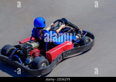 Karting in gara all'aria aperta. Donna al volante di un kart. La ragazza corre su un kart ad alta velocità. Foto Stock