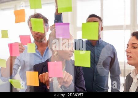 Giovani uomini d'affari come un team creativo brainstorming con appiccicoso note Foto Stock