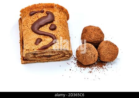 Caramelle al cioccolato fatte in casa e rotolo, isolarsi su sfondo bianco. Involtini e caramelle ricoperse di cioccolato. Prodotti di cioccolato deliziosi primo piano. Foto Stock