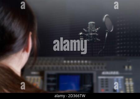 Ragazza ingegnere del suono seduto alla tavola di mescolamento. Luogo di lavoro in un vero studio di registrazione. Lavoro professionale con l'audio sulla console del Director. Il professionista Foto Stock