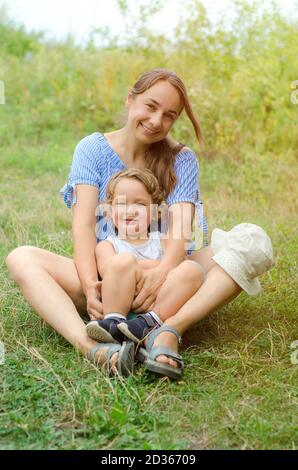 madre e bambino seduti su un'erba su un soleggiato giorno Foto Stock