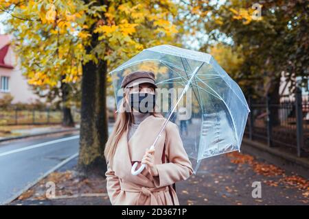 Donna con un ombrello a piedi lungo la strada in un giorno di pioggia Foto  stock - Alamy