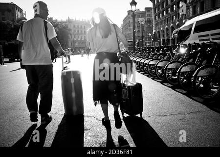 Uomo e donna che camminano in una strada con le valigie con ruote. Foto Stock