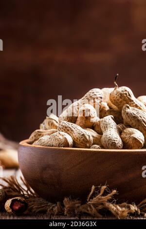 Arachidi in conchiglia, sfondo in legno vintage, fuoco selettivo Foto Stock