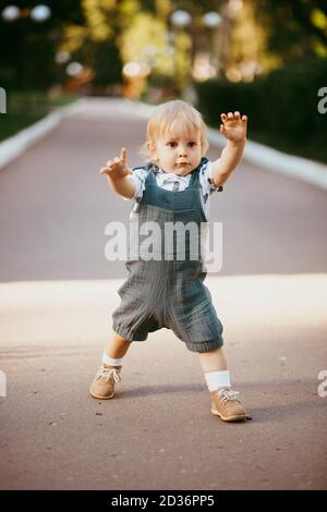 un bambino felice vestito con un jumpsuit di mussola sta riposando sull'erba verde. Foto Stock