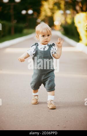 un bambino felice vestito con un jumpsuit di mussola sta riposando sull'erba verde. Foto Stock