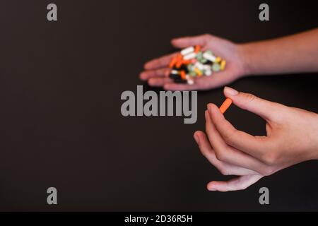 Pillole colorate e farmaci in fondo nero handson. Luogo per un'iscrizione. Foto Stock