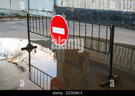 Segnale stradale Nessun ingresso per il traffico veicolare su stand in metallo in puddle vicino edificio Foto Stock