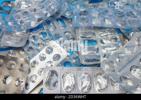 Molte confezioni blister usate senza pillole su sfondo blu. Concetto medico e sanitario Foto Stock