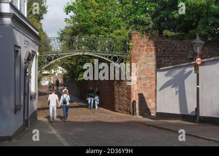 Exeter Devon estate, vista di persone che passano sotto il ponte di ferro Burnett Patch all'ingresso della Cattedrale vicino a Exeter, Devon, Inghilterra, Regno Unito Foto Stock