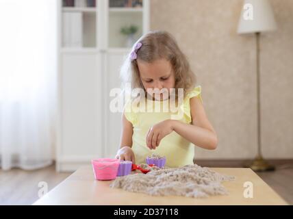 carino bambina che gioca con sabbia cinetica e muffe di sabbia Foto Stock