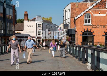 Eton, Buckinghamshire, Inghilterra, Regno Unito. 2020. Il ponte Windsor ed Eton si trova tra le due città. Turisti e acquirenti alcune maschere che indossano si incrociano Foto Stock