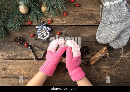 Composizione natalizia con le mani dei bambini in mittens, calzini di lana e giocattoli di Natale su sfondo naturale di legno. Foto Stock